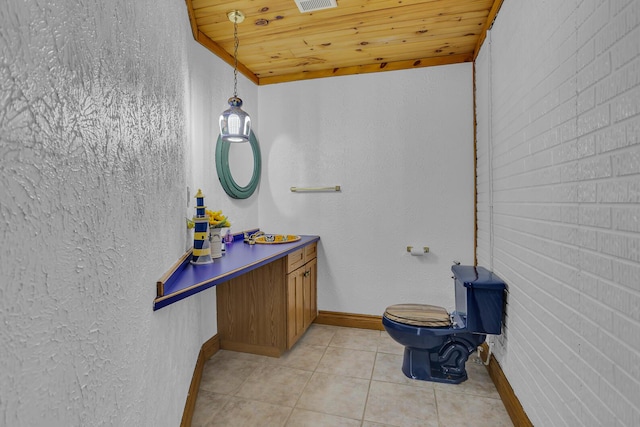 half bath with toilet, vanity, brick wall, tile patterned flooring, and wood ceiling