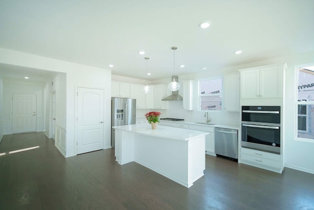 kitchen featuring a sink, white cabinets, appliances with stainless steel finishes, a center island, and dark wood-style floors