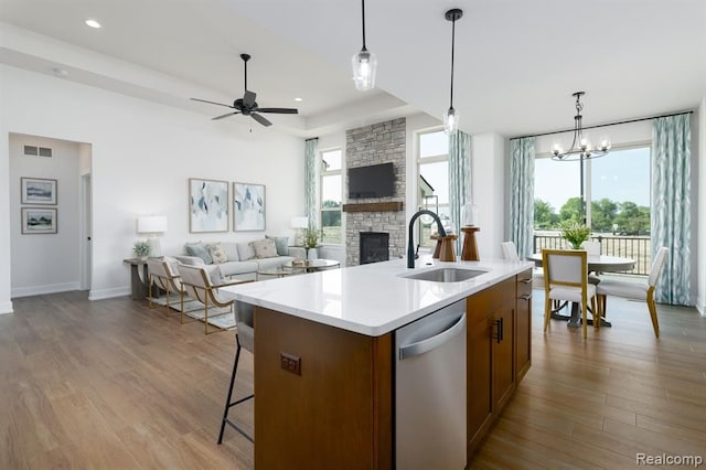 kitchen with dishwasher, a fireplace, a sink, ceiling fan with notable chandelier, and open floor plan