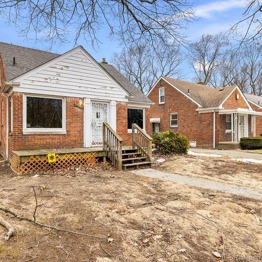 bungalow-style home with a shingled roof and brick siding