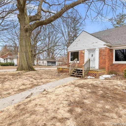 view of front of home with a wooden deck, brick siding, and roof with shingles