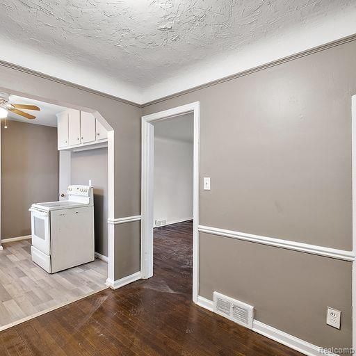 interior space with white cabinetry, light wood-type flooring, range, ceiling fan, and visible vents