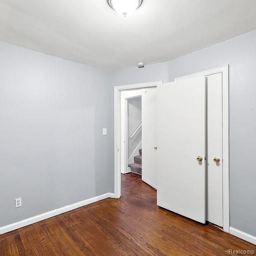 spare room with baseboards, wood finished floors, and stairway