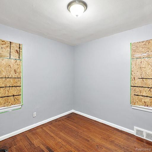 unfurnished room featuring wood finished floors, baseboards, and visible vents