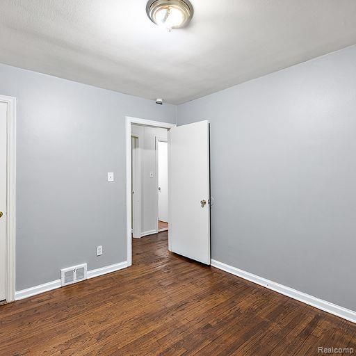 spare room with baseboards, visible vents, and wood finished floors