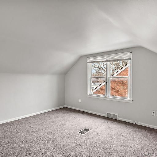 additional living space with baseboards, visible vents, and carpet floors