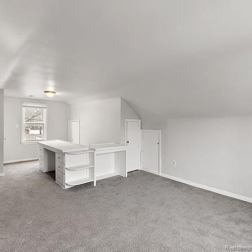 additional living space featuring baseboards, vaulted ceiling, and carpet