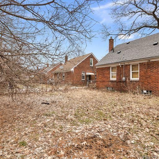 back of house with a chimney and brick siding