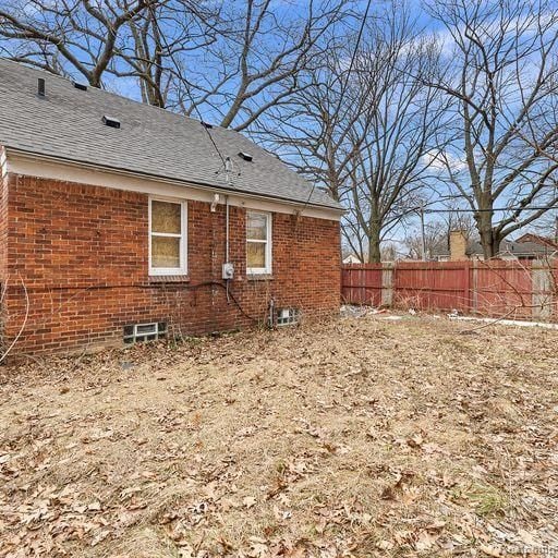 back of property featuring brick siding and fence