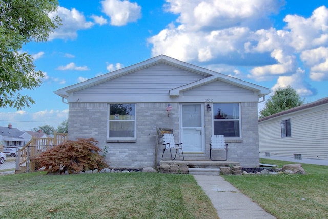 bungalow with a front lawn, fence, and brick siding