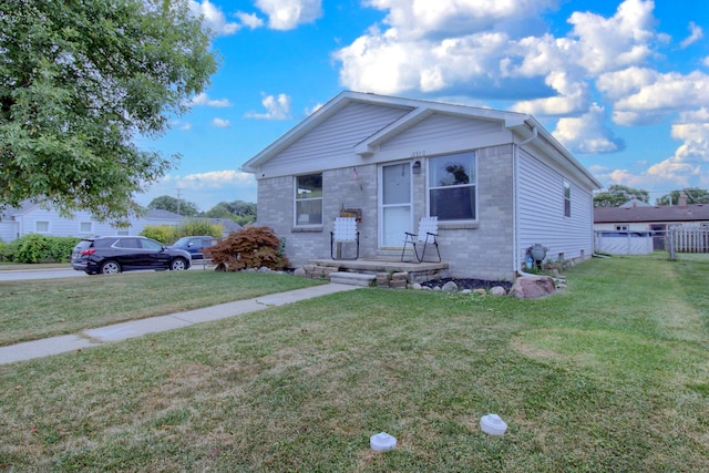 bungalow-style house featuring brick siding, fence, and a front lawn