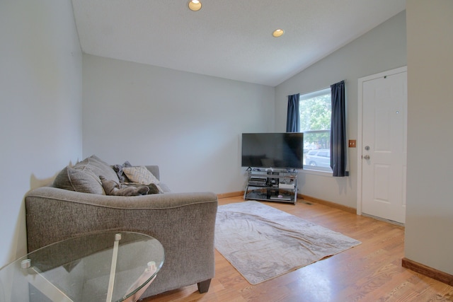 living room with lofted ceiling, baseboards, and light wood-style floors