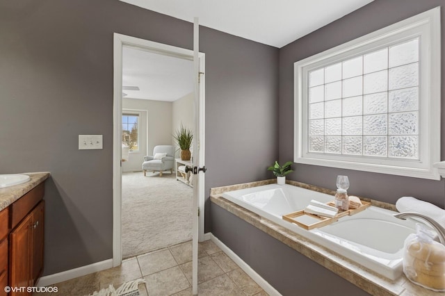 bathroom featuring a garden tub, vanity, baseboards, and tile patterned floors