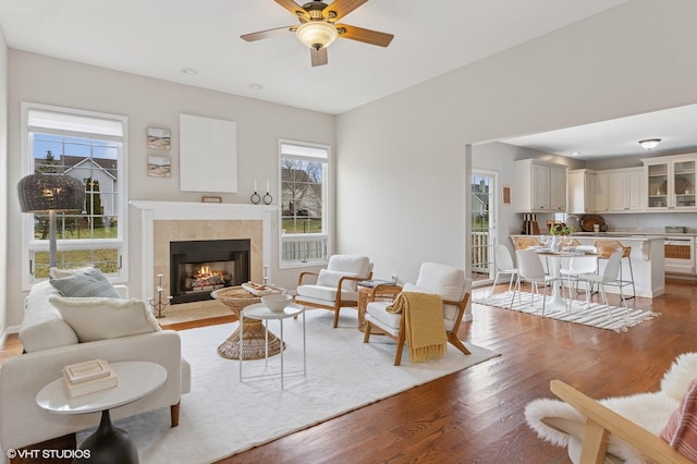 living area featuring a ceiling fan, wood finished floors, and a tile fireplace