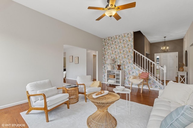 living room with stairs, an accent wall, baseboards, and wood finished floors