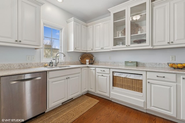 kitchen with white cabinets, glass insert cabinets, wood finished floors, stainless steel dishwasher, and a sink