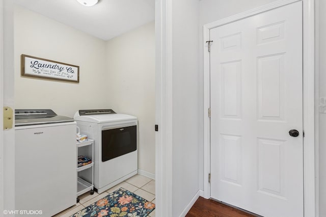 laundry area with laundry area, washing machine and dryer, baseboards, and light tile patterned flooring