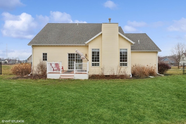 back of house with a shingled roof, fence, and a lawn