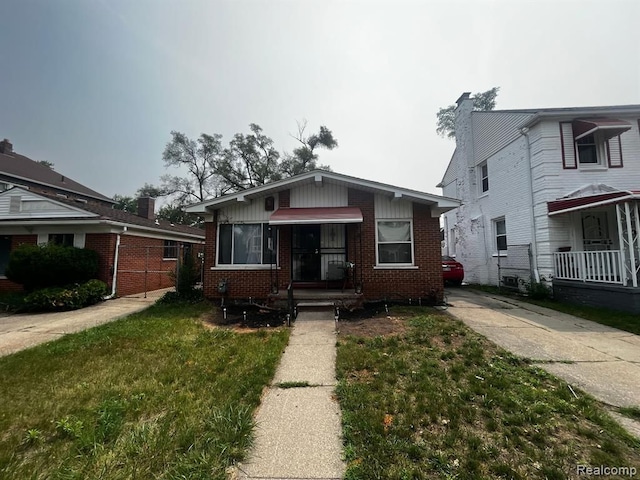 bungalow with a front yard and brick siding