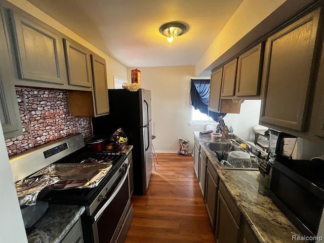 kitchen with stainless steel gas range oven, baseboards, dark wood finished floors, a sink, and backsplash