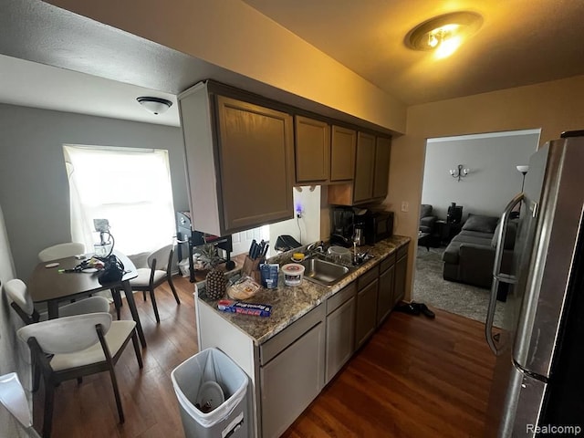 kitchen with black microwave, dark wood-type flooring, a sink, and freestanding refrigerator