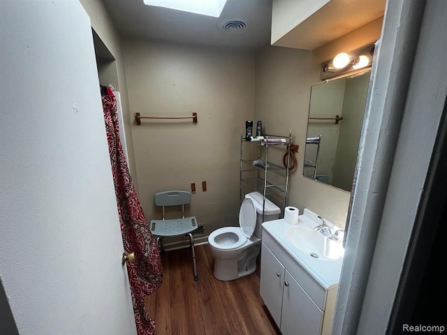 bathroom featuring a skylight, visible vents, toilet, vanity, and wood finished floors