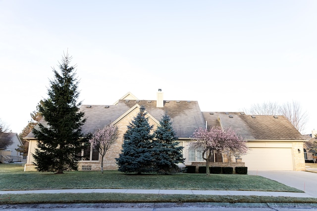 view of front facade featuring driveway, an attached garage, a chimney, and a front lawn