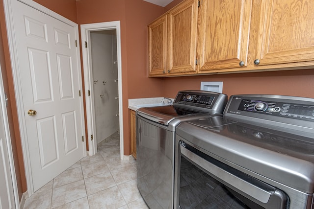 laundry area with a sink, light tile patterned flooring, washing machine and dryer, and cabinet space