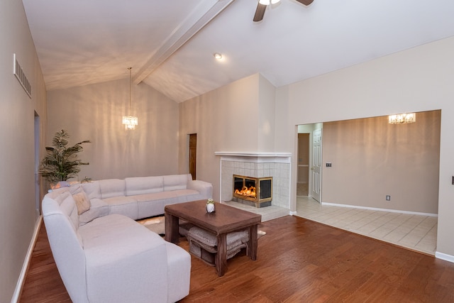 living room featuring a tile fireplace, wood finished floors, visible vents, baseboards, and beamed ceiling