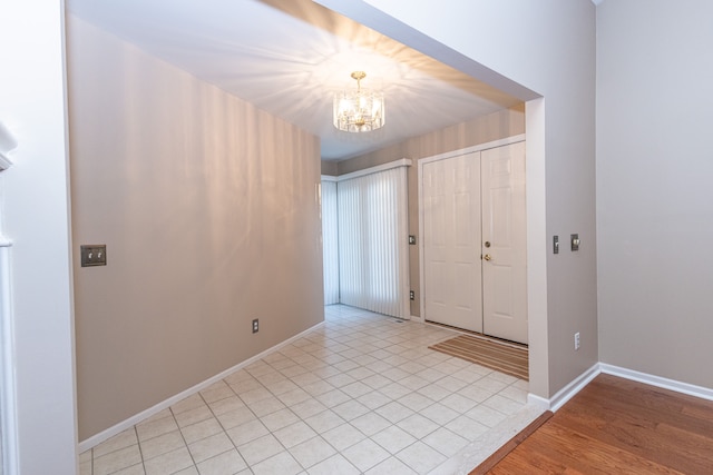 foyer with baseboards, a chandelier, and light tile patterned flooring