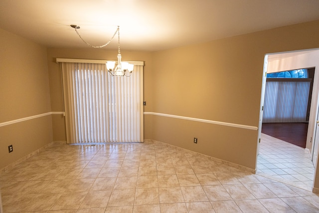 unfurnished room featuring light tile patterned floors and a chandelier