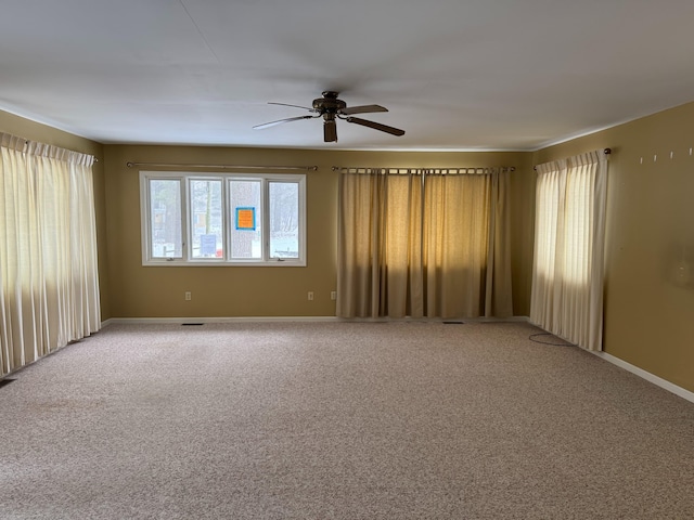 empty room with carpet floors, visible vents, baseboards, and a ceiling fan