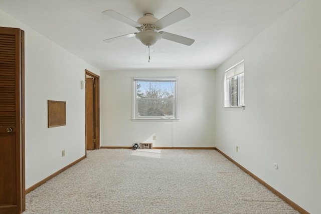 carpeted empty room with visible vents, ceiling fan, and baseboards