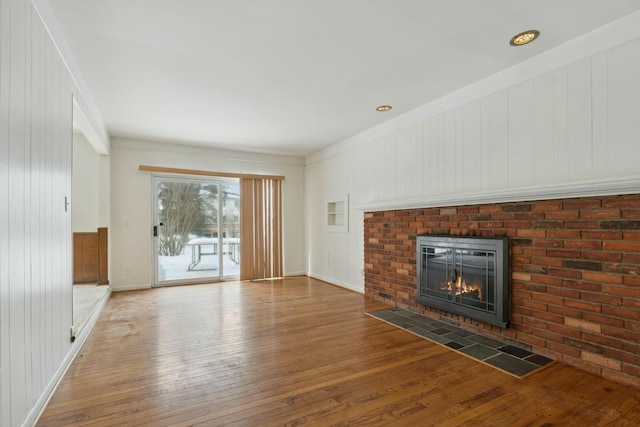 unfurnished living room featuring hardwood / wood-style flooring, a fireplace, and baseboards