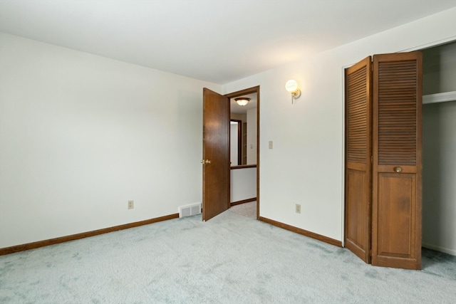 unfurnished bedroom featuring light carpet, a closet, visible vents, and baseboards