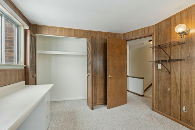 bedroom with light carpet, wood walls, a closet, and baseboards