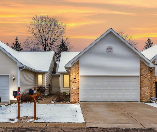 ranch-style house with concrete driveway, brick siding, and an attached garage