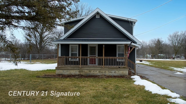 view of front of house with covered porch, a lawn, and fence