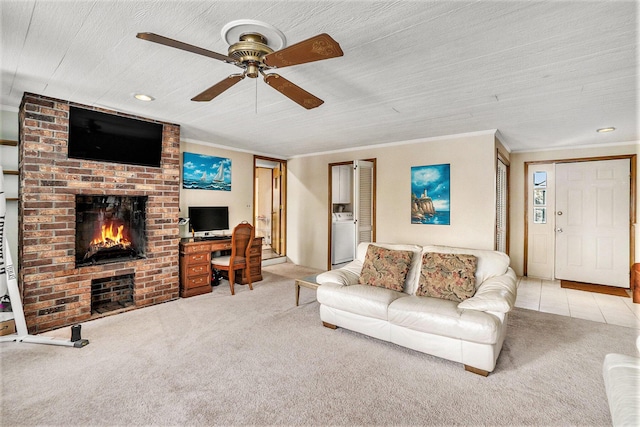 carpeted living room featuring a brick fireplace, tile patterned flooring, washer / clothes dryer, and crown molding