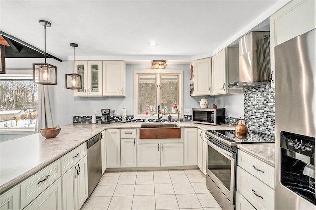 kitchen featuring light tile patterned floors, stainless steel appliances, tasteful backsplash, a sink, and wall chimney exhaust hood