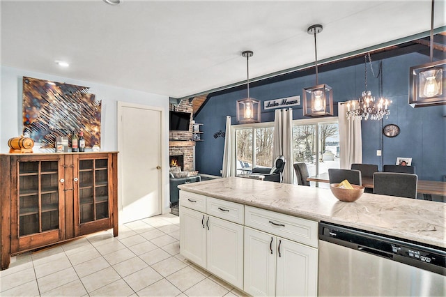 kitchen with pendant lighting, stainless steel dishwasher, white cabinets, light tile patterned flooring, and a stone fireplace