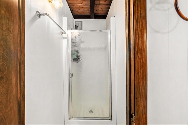 full bathroom featuring wood ceiling, beamed ceiling, and a shower stall