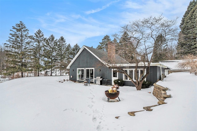 snow covered house with a fire pit and a chimney