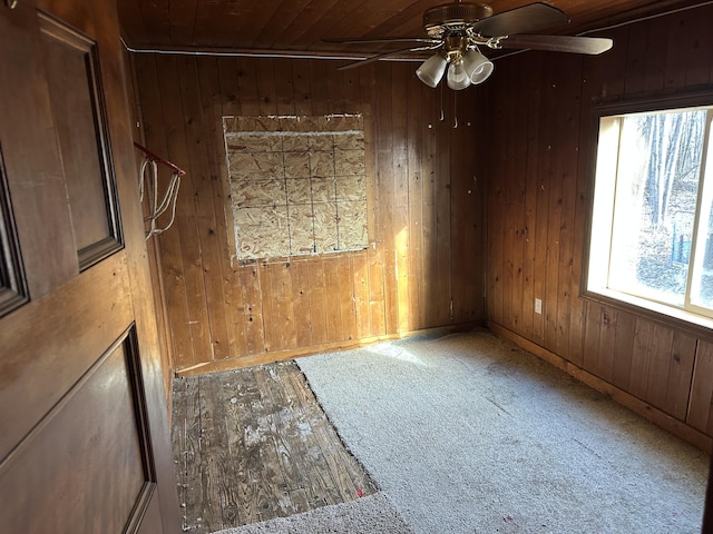 unfurnished room featuring wood ceiling, wooden walls, a ceiling fan, and wood finished floors