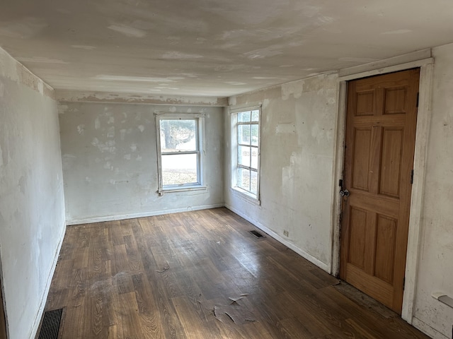 spare room featuring wood finished floors, visible vents, and baseboards