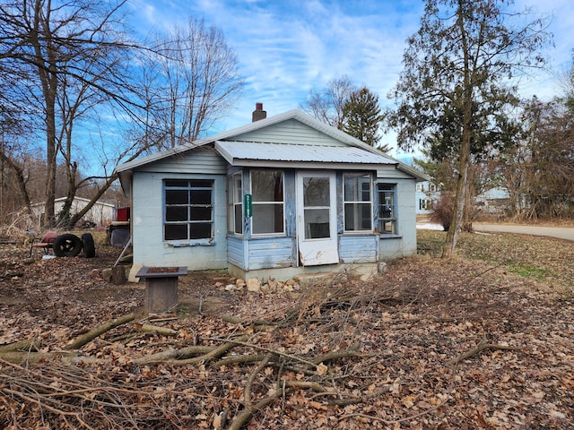 view of front of home with concrete block siding, metal roof, and a chimney