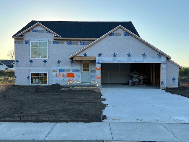 unfinished property featuring a garage and concrete driveway