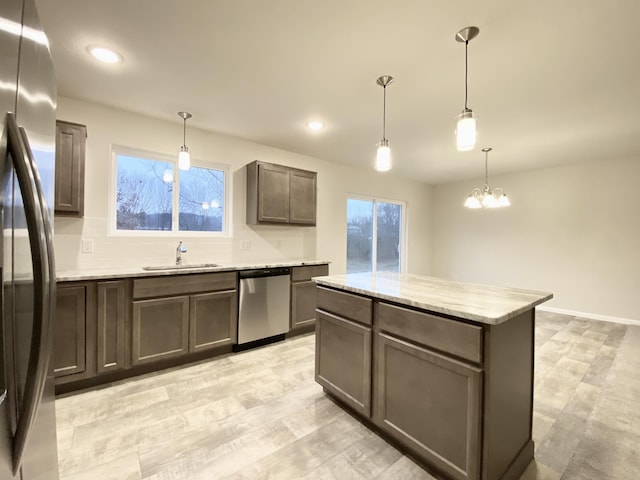 kitchen featuring appliances with stainless steel finishes, a center island, a healthy amount of sunlight, and a sink