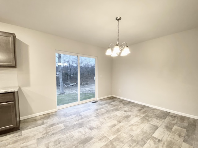 unfurnished dining area with light wood-style floors, baseboards, and a notable chandelier