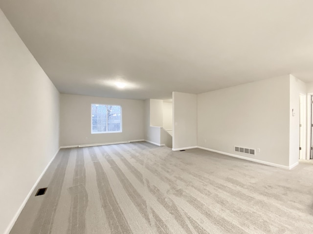 unfurnished living room with light colored carpet, visible vents, and baseboards